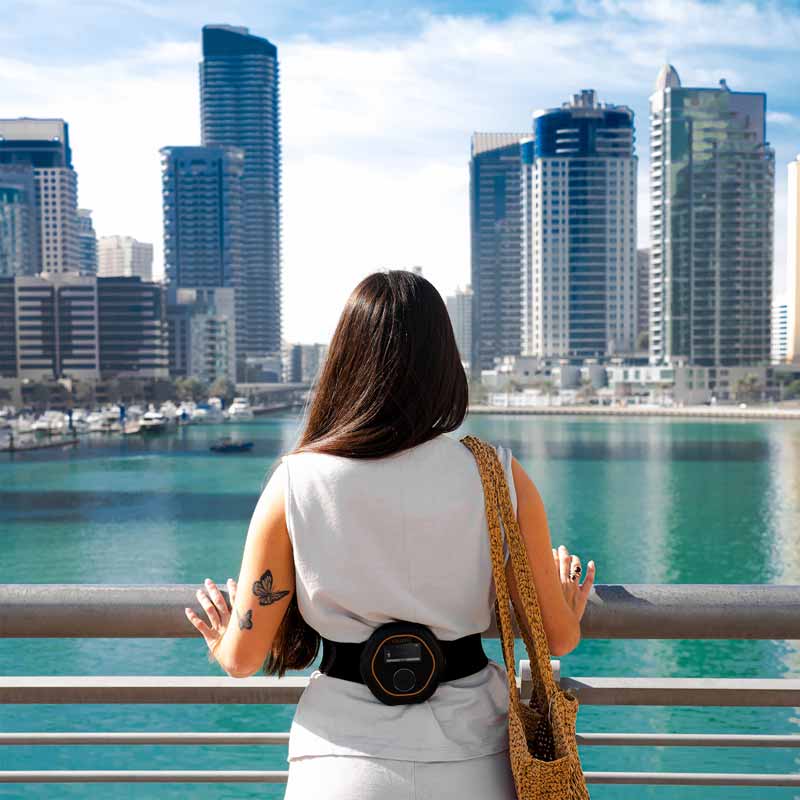 CELLER8 localised PEMF therapy device worn around back while women looks over Dubai marina